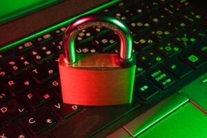 Red padlock resting on a laptop keyboard lit in green