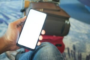 Person holding a smartphone in an airport with luggage, representing eSIM travel connectivity
