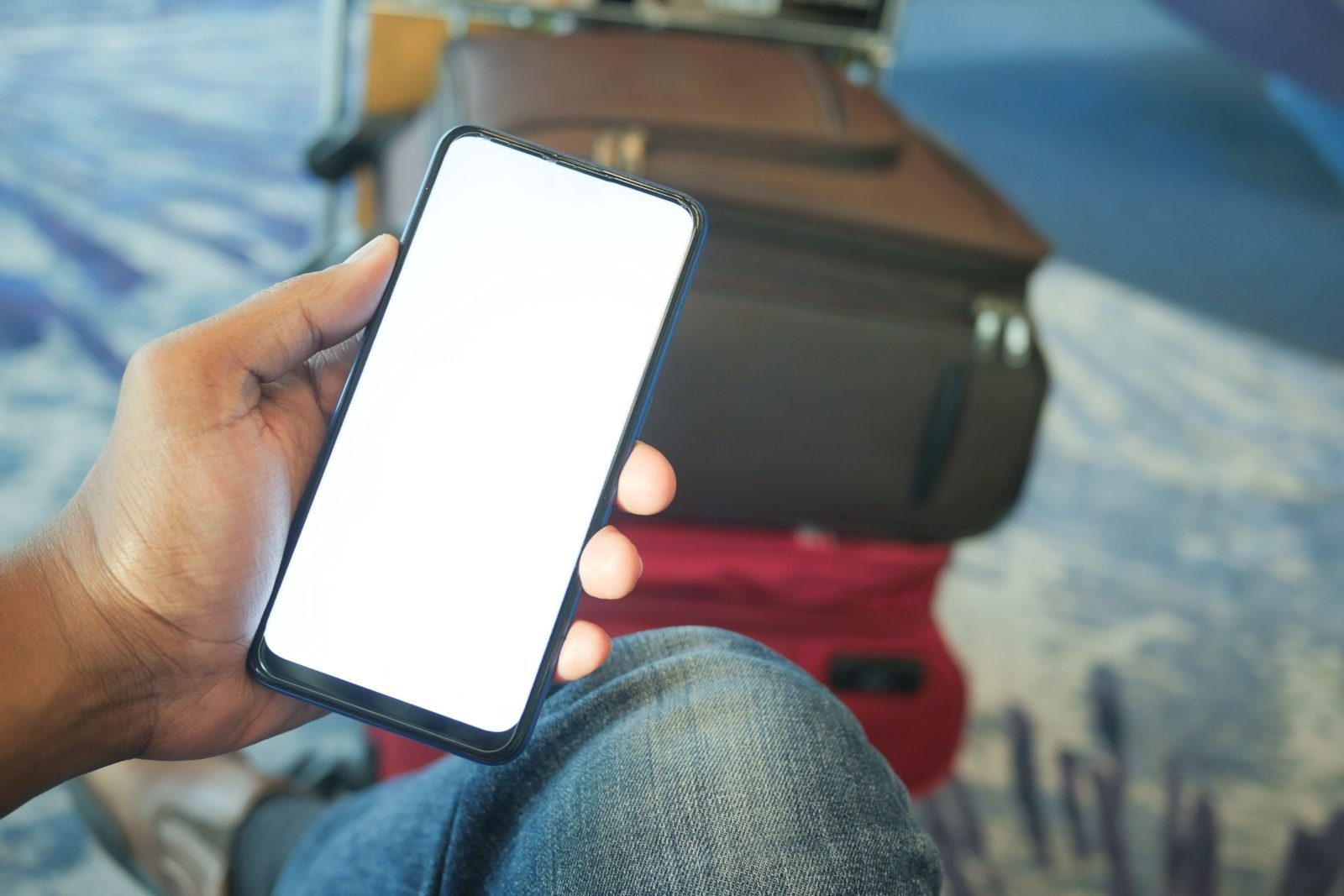 Person holding a smartphone in an airport with luggage, representing eSIM travel connectivity
