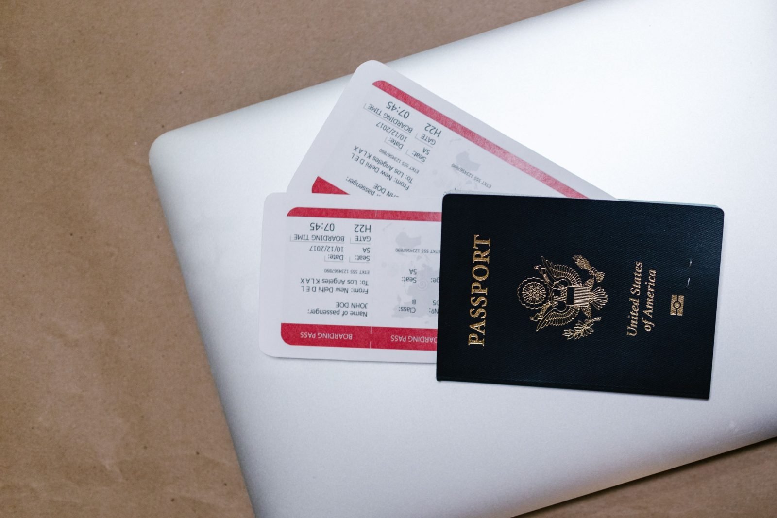 Passport and boarding passes resting on a laptop, representing digital nomad visa travel preparation