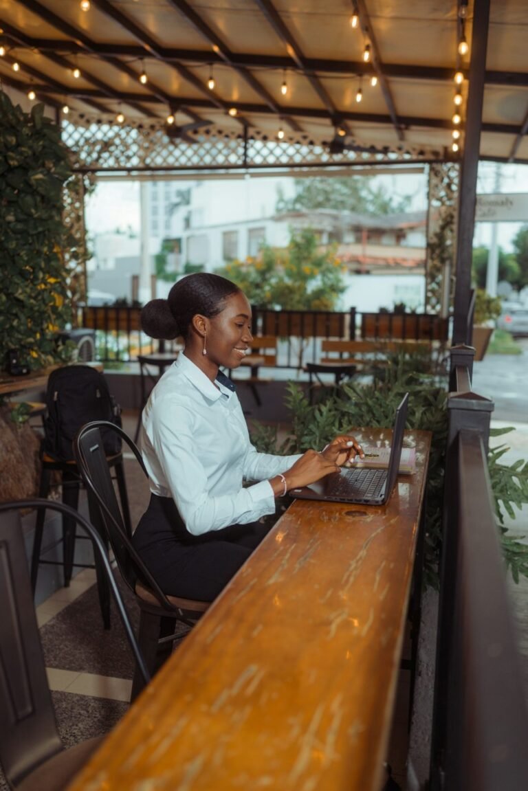 Digital nomad typing on a laptop keyboard at an outdoor cafe