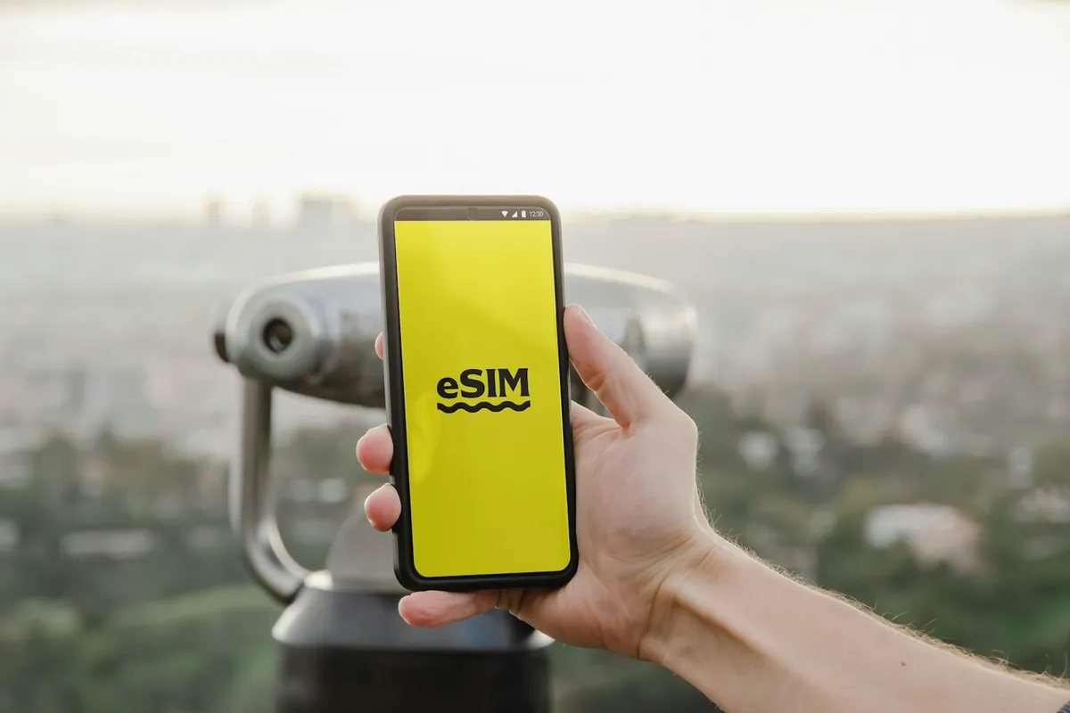 Reisender hält an einem Stadtaussichtspunkt ein Handy mit eSIM-Bildschirm