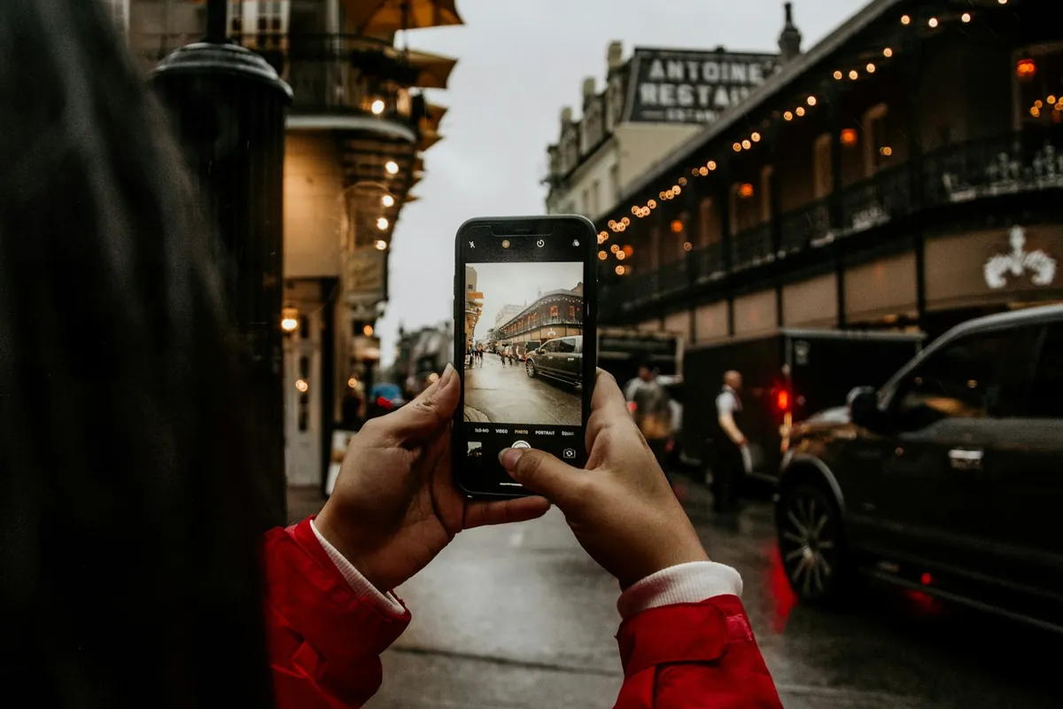 Traveler taking a phone photo on a city street