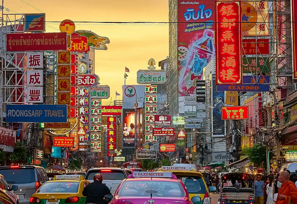 Leuchtreklamen und Verkehr auf der Yaowarat Road in Bangkoks Chinatown in der Abenddämmerung