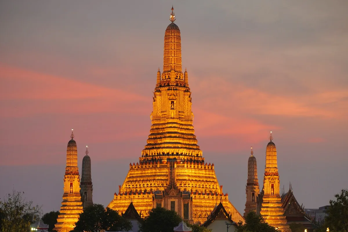 Der Wat Arun-Tempel, golden beleuchtet bei Sonnenuntergang über dem Chao Phraya