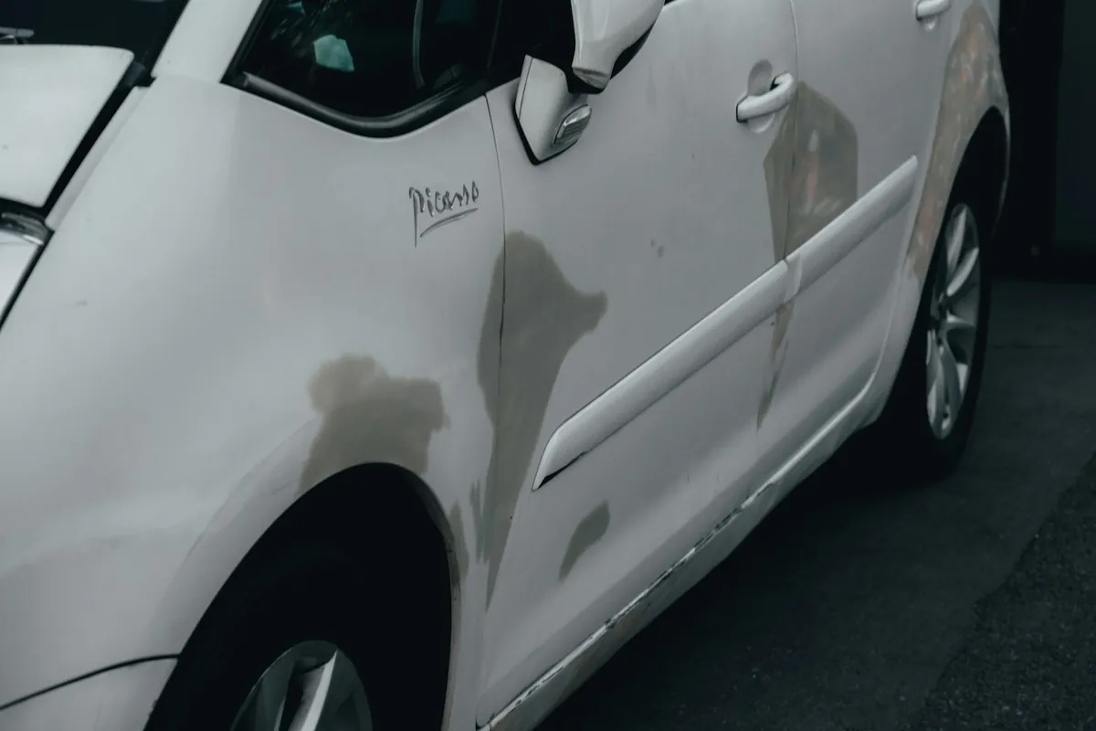 Dent and scrape along the side door of a white car