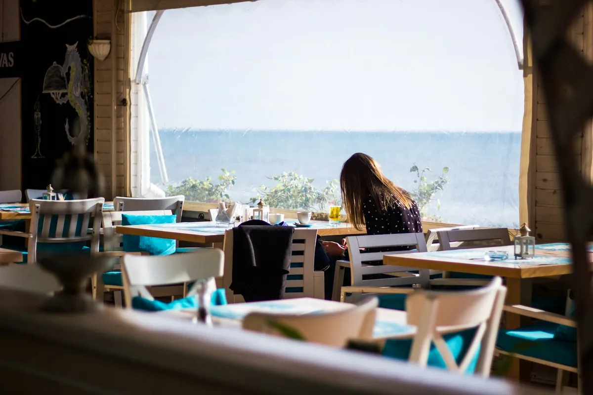 Woman working alone at a seaside cafe table