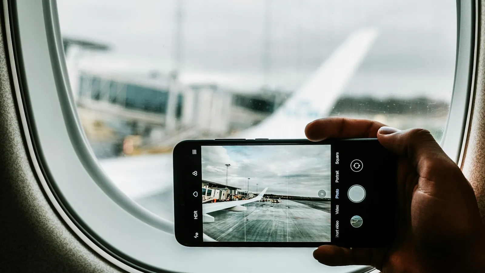 Phone photographing a plane wing through the airplane window