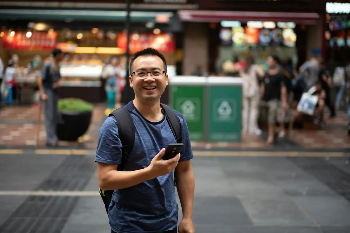 Smiling traveler holding a smartphone on a city street