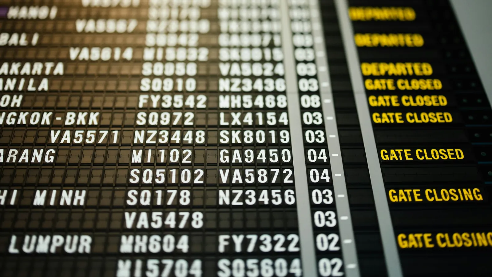 Airport departures board with gate closing notices for flights across Asia