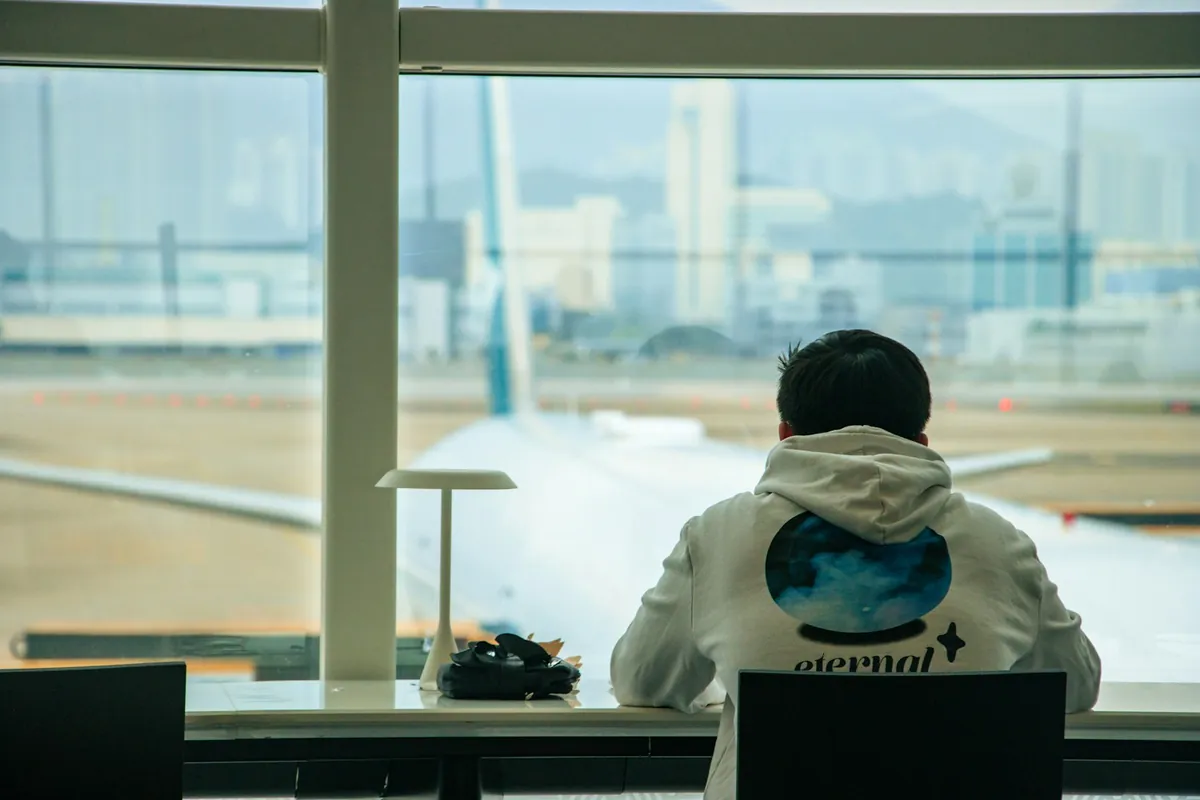 Traveler at an airport window watching a plane on the apron
