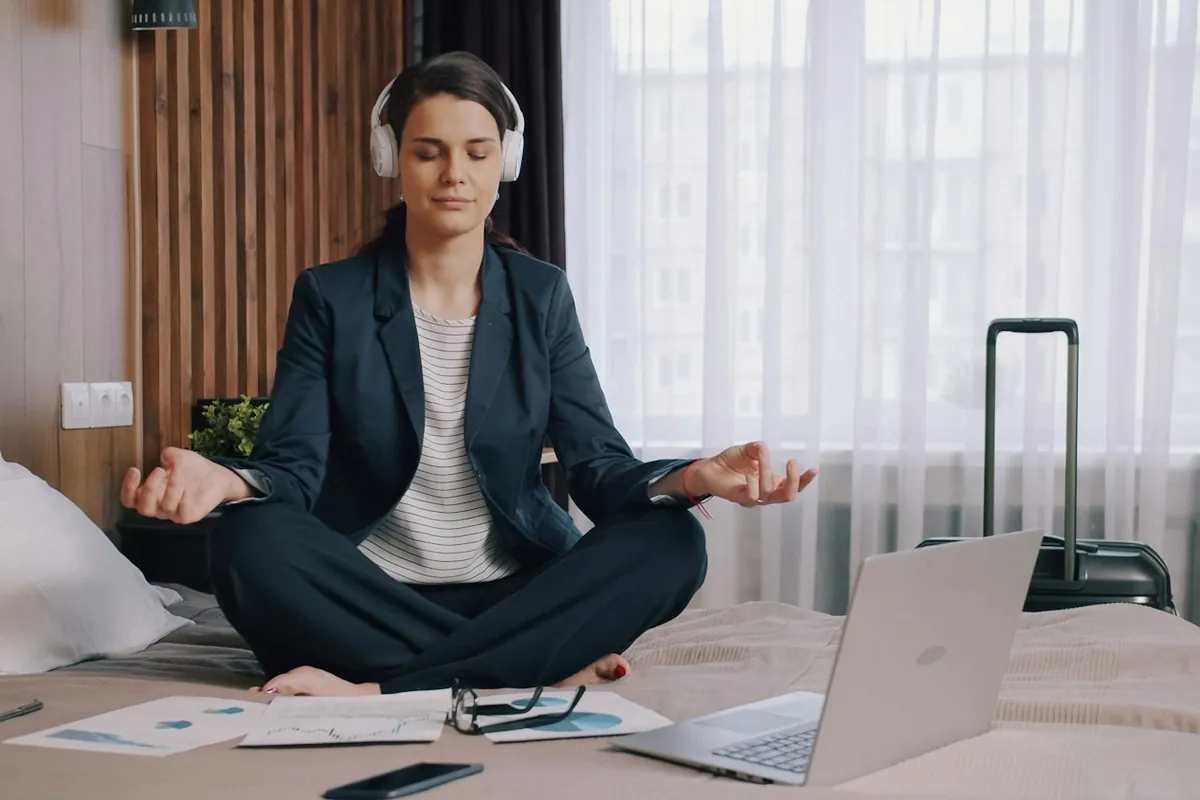 Digital nomad using a meditation app on a hotel bed