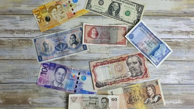 Banknotes from several different countries spread out on a wooden table
