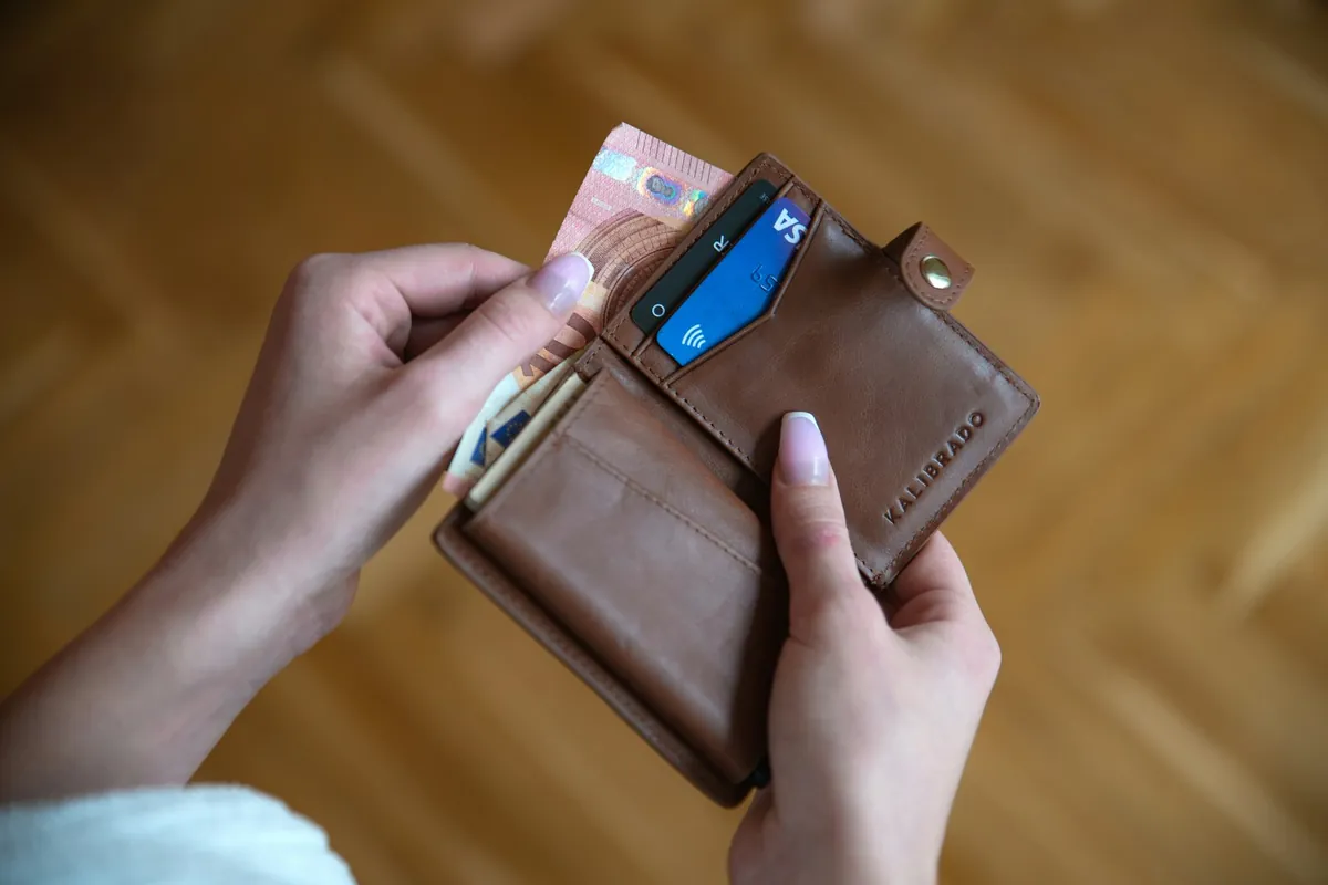 Hand holding a brown leather card wallet
