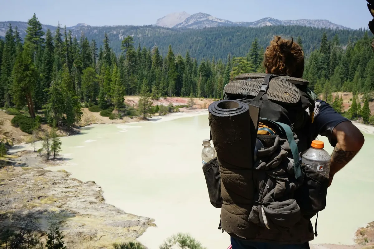 Hiker with a large backpack standing near a mountain lake