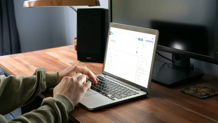 Person working in the WordPress editor on a laptop at a wooden desk