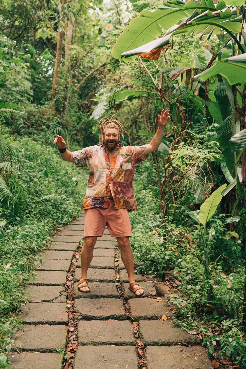 Chenzo, founder of NomadsToolsLab, spreading his arms on a stone path through the jungle