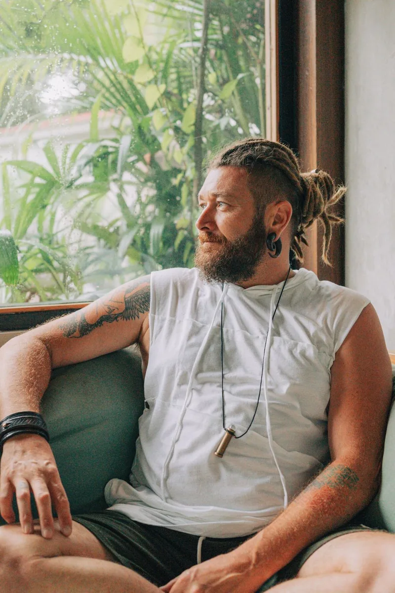 Chenzo, founder of NomadsToolsLab, relaxing on a sofa by a window full of greenery
