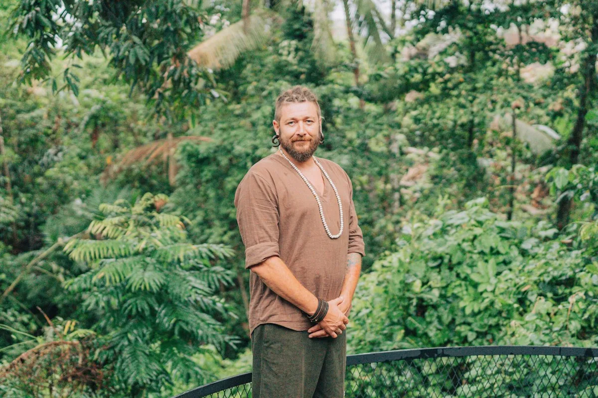 Chenzo, founder of NomadsToolsLab, standing on a terrace surrounded by lush green forest