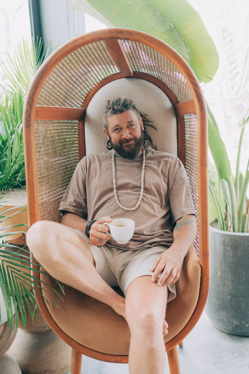 Chenzo, founder of NomadsToolsLab, relaxing with a cup of coffee in a rattan chair