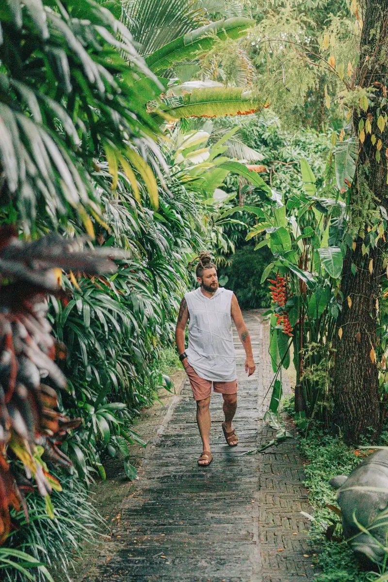 Chenzo, founder of NomadsToolsLab, walking along a path between tall tropical plants