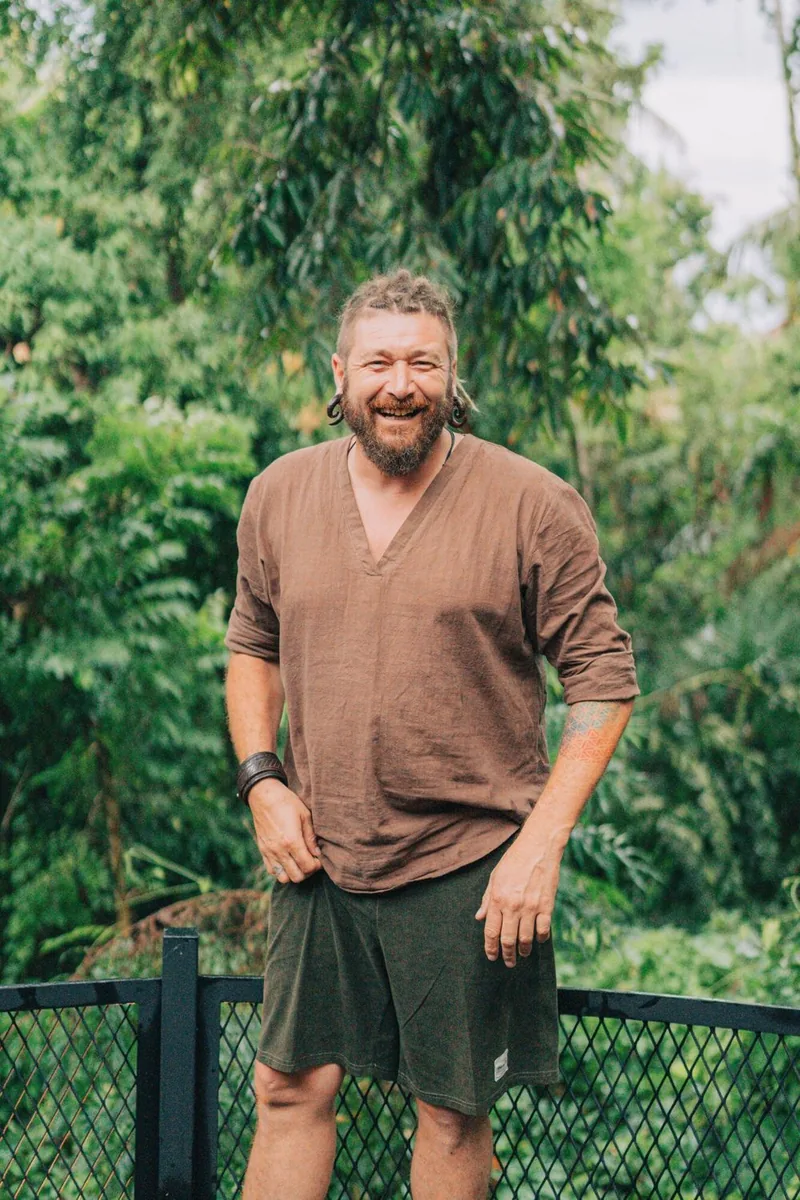 Chenzo, fundador de NomadsToolsLab, sonriendo al aire libre frente a árboles de la jungla verde