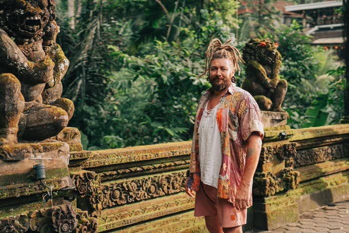 Chenzo, founder of NomadsToolsLab, standing next to a stone temple carving in Bali