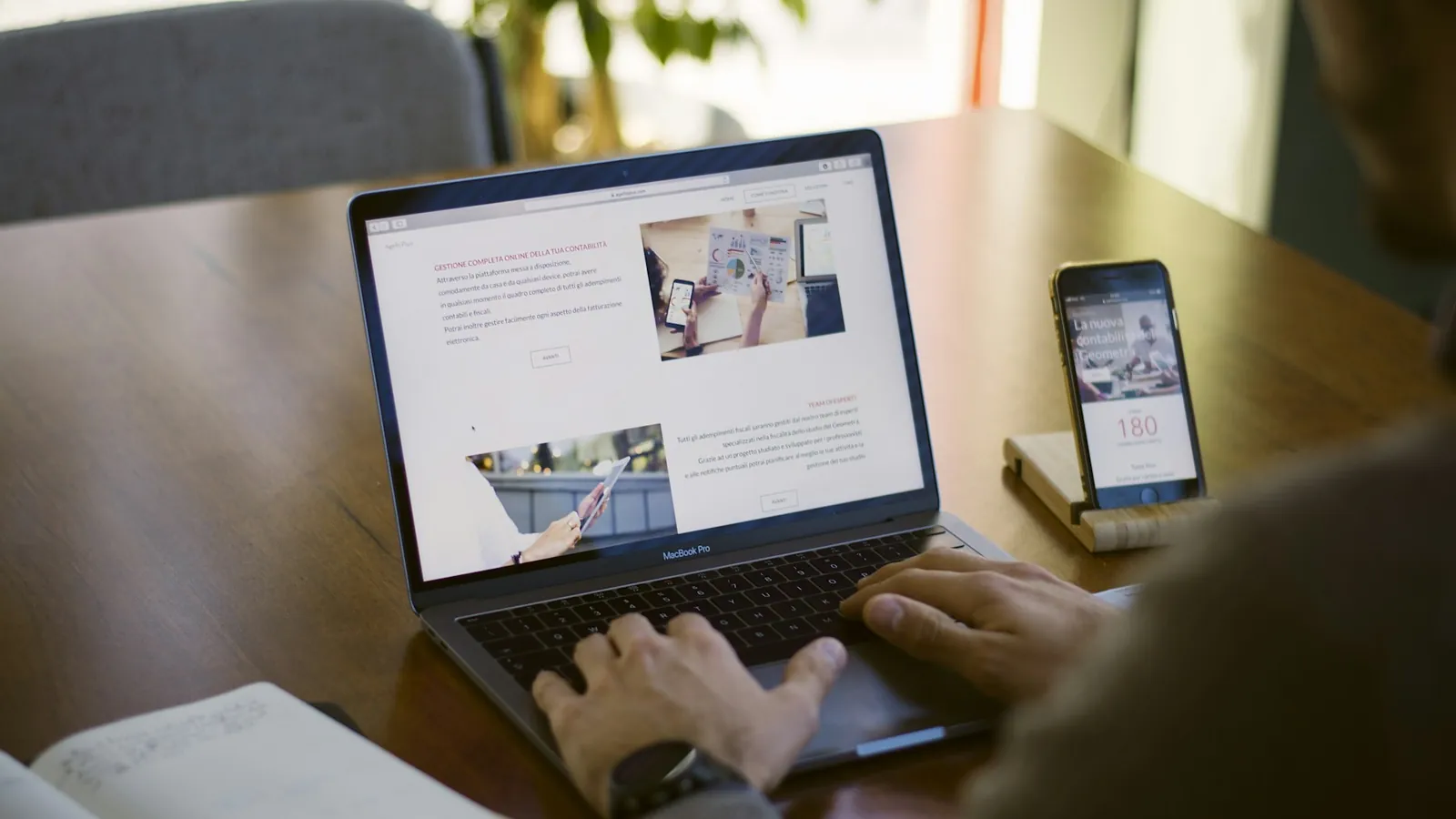 Creator working on a laptop with a phone beside it, writing an email newsletter