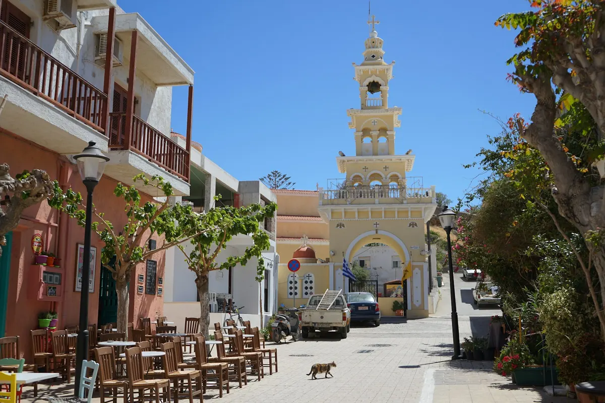 Greek town square with a church tower and cafe tables in Crete, Crete digital nomad guide