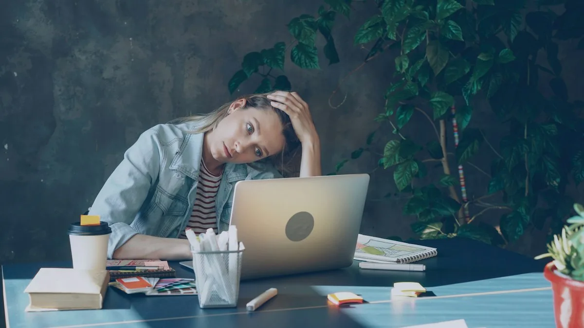 Tired remote worker holding her head at a laptop, a sign of digital nomad burnout