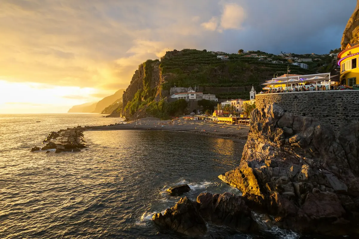 Puesta de sol sobre acantilados y casas en la costa de Madeira