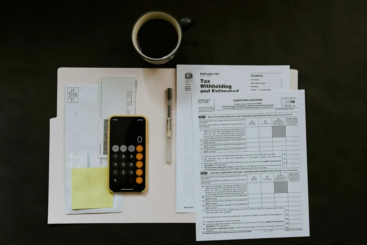 Tax withholding form, phone calculator and coffee on a desk