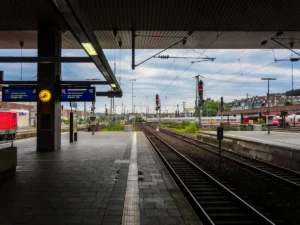 An empty platform with train tracks and overhead wires at a European train station