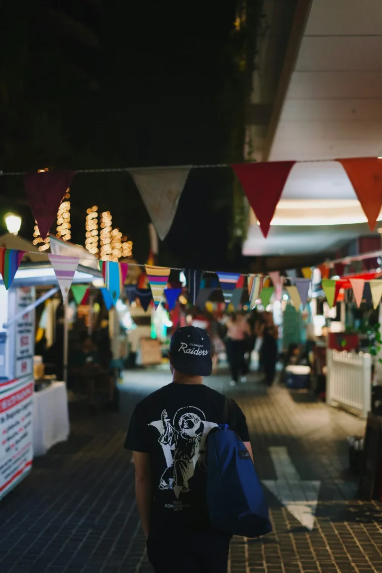 Backpacker geht mit einer Tasche über der Schulter durch einen belebten Nachtmarkt