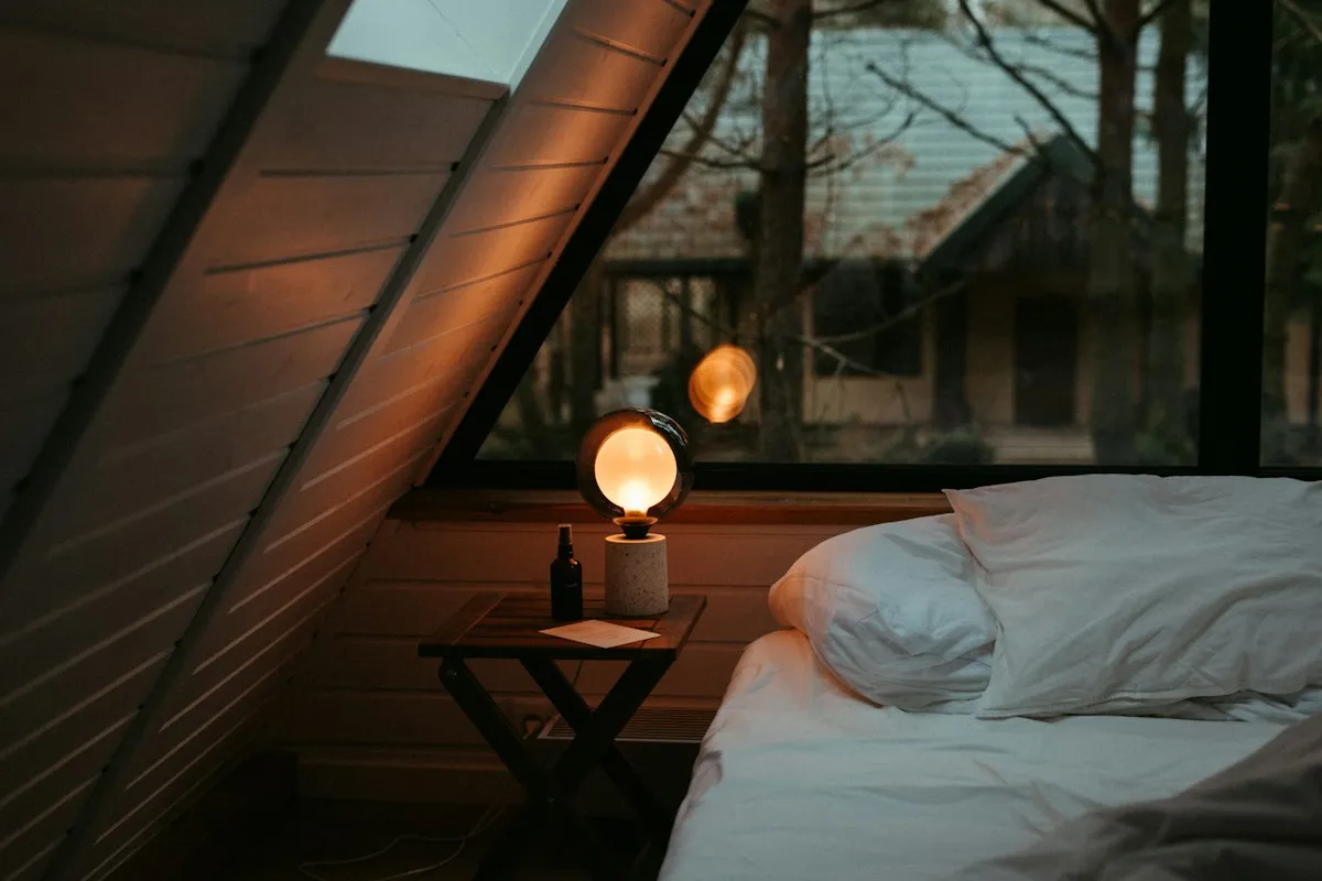 Quiet private room with a bed under a window and a small lamp, a calm base for a highly sensitive digital nomad