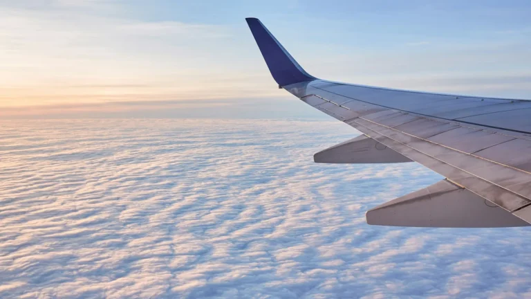 Airplane wing above white clouds seen from a window seat