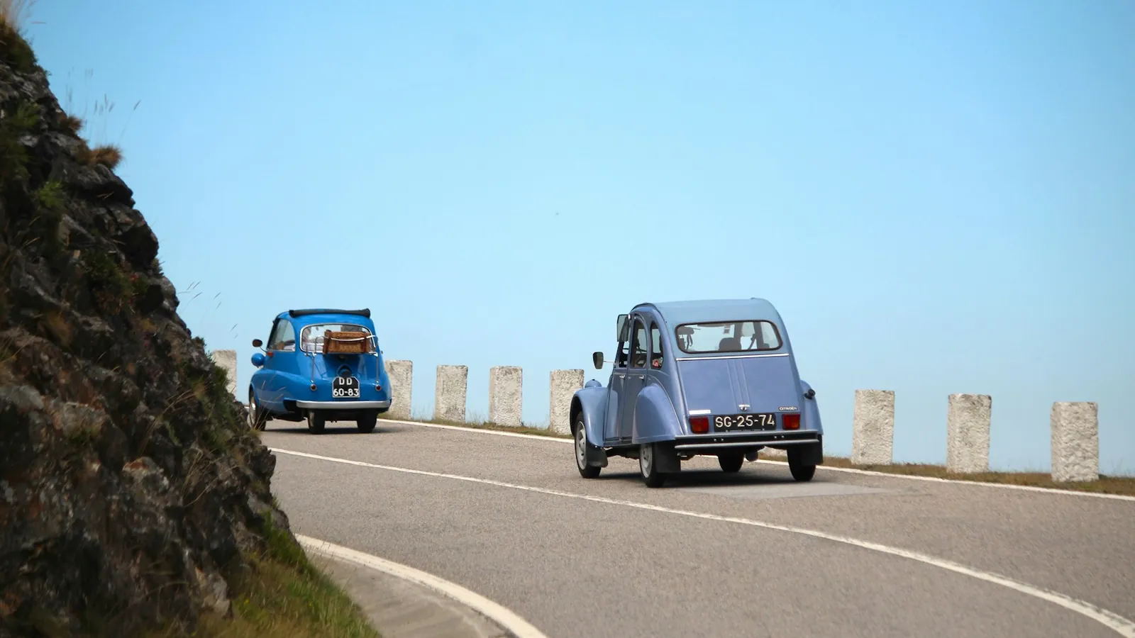 Two classic cars driving along a mountain road in Portugal