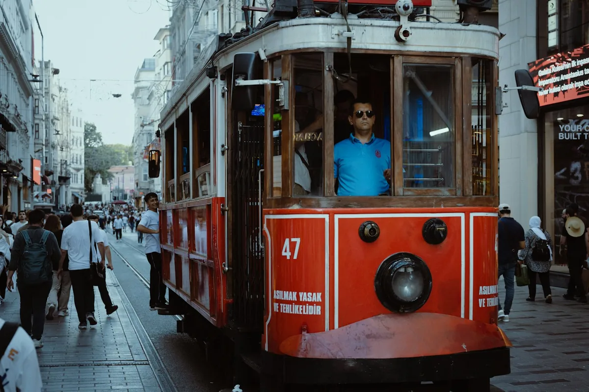 A red vintage tram moving through a crowded pedestrian street in Istanbul