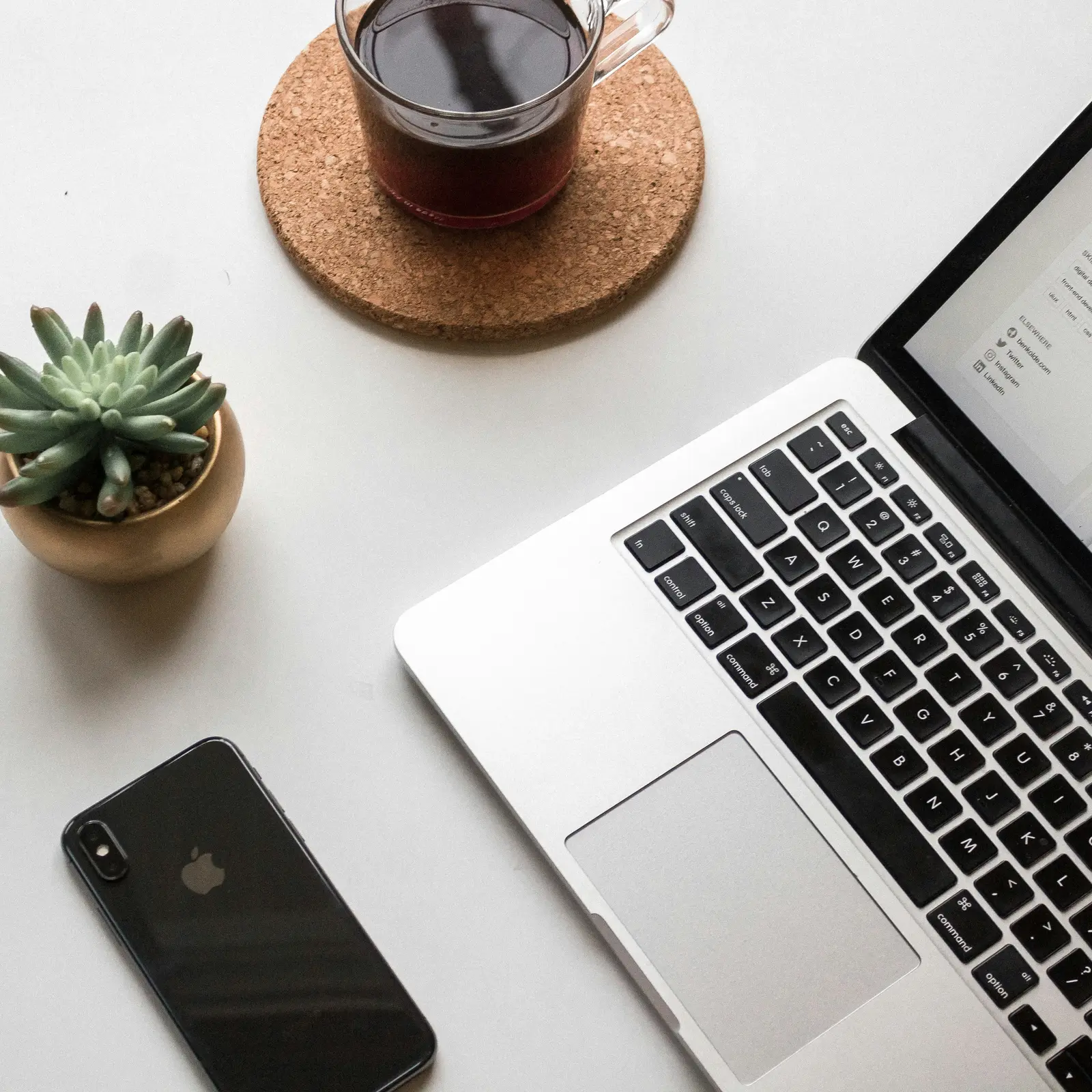 Laptop and phone side by side on a desk with coffee