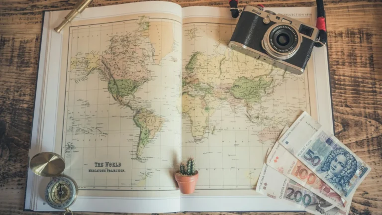 Vintage world map with a camera, compass and banknotes for planning a multi-city trip