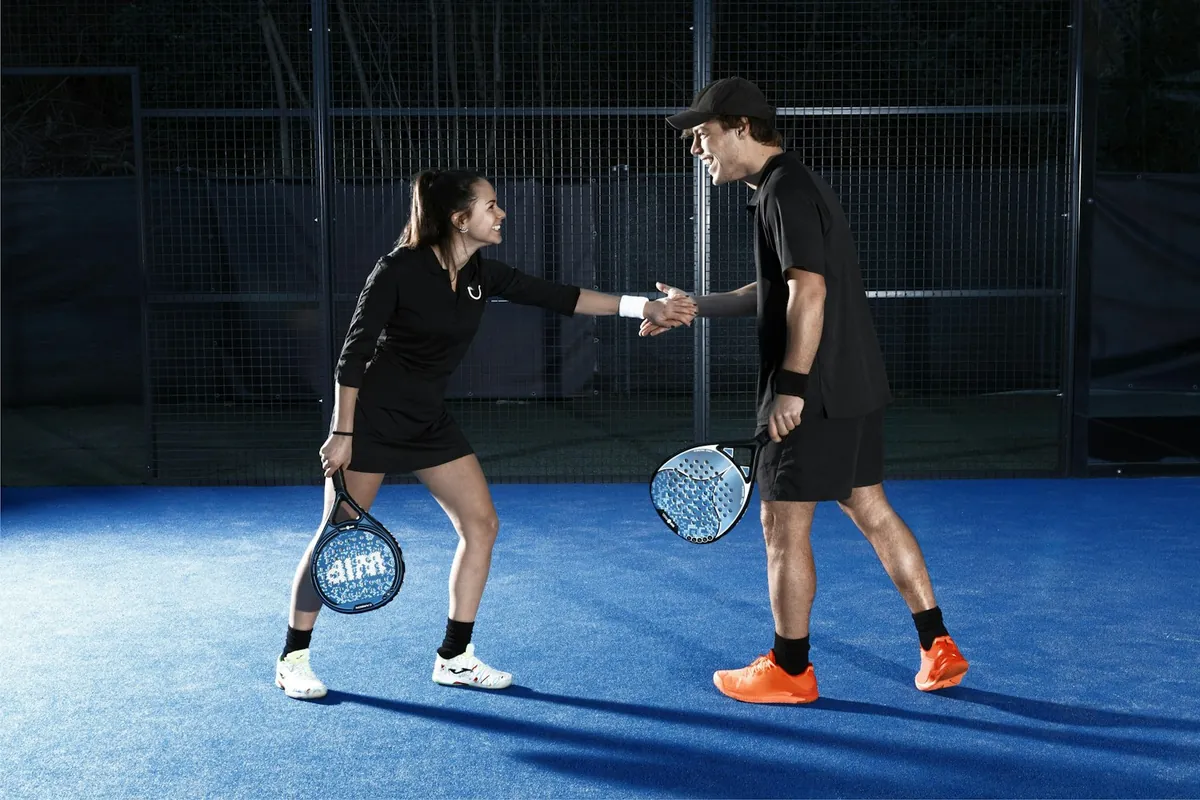 Two padel partners shaking hands on court before a doubles match