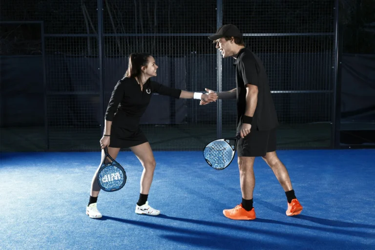 Two padel players shaking hands courtside after a match