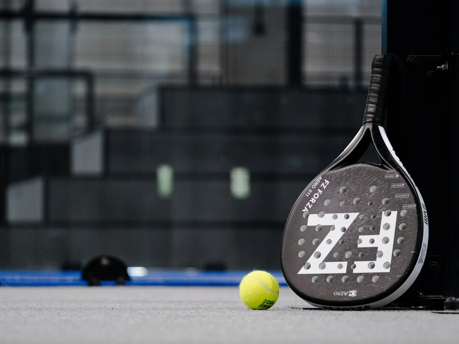 Pala y pelota de pádel sobre la superficie de la pista