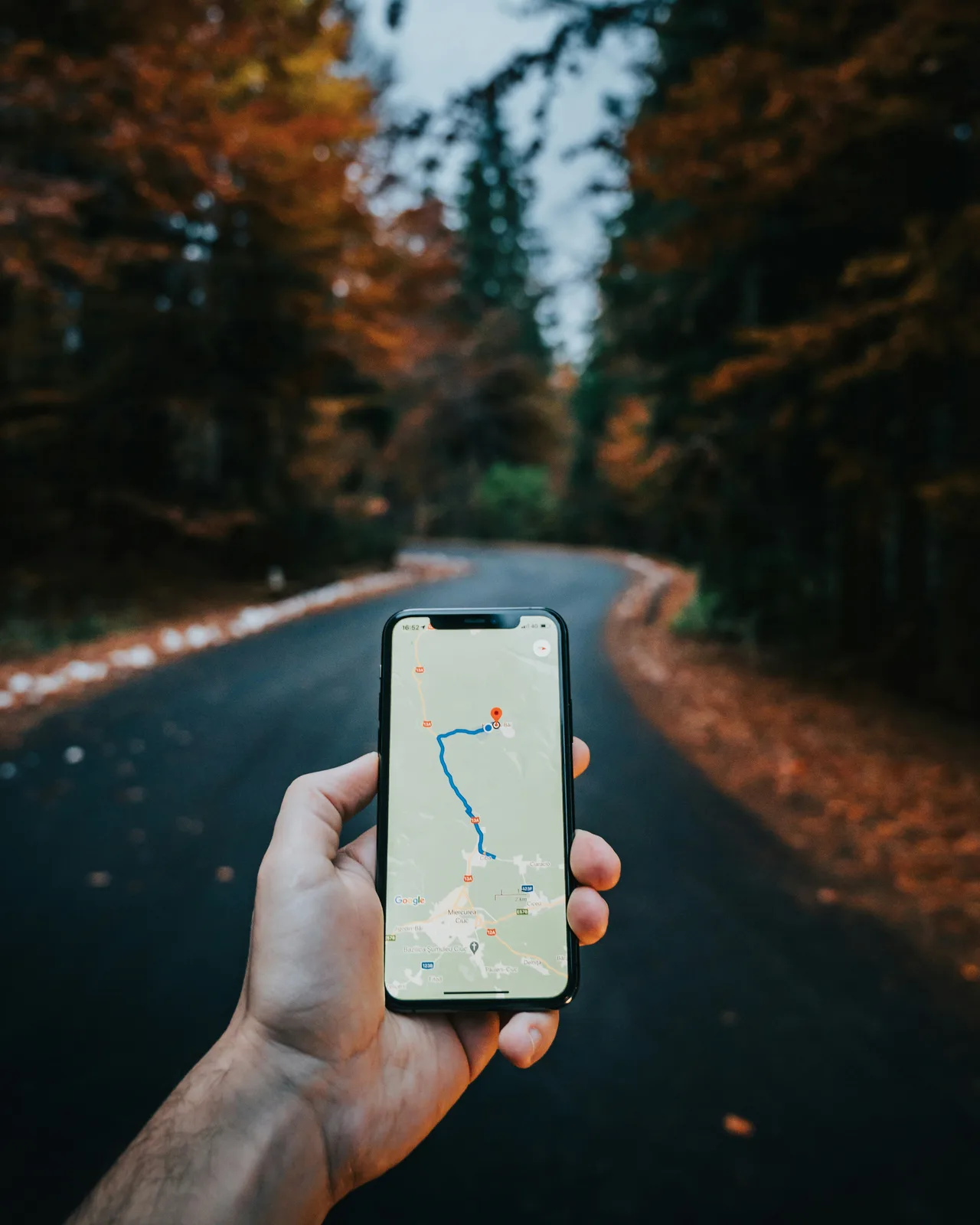 Hand hält ein Smartphone mit geöffneter Navigationskarte auf einer Straße