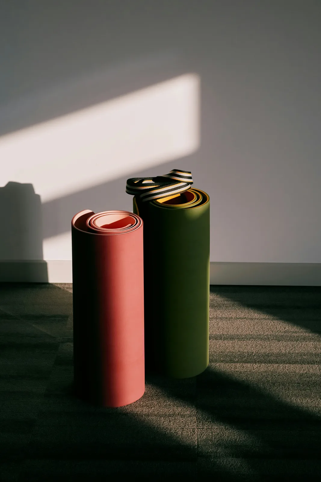 Dos esterillas de yoga de viaje enrolladas apoyadas contra una pared
