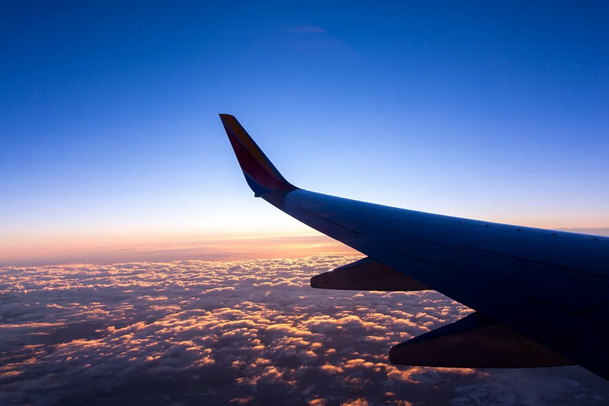Airplane wing above the clouds at sunrise