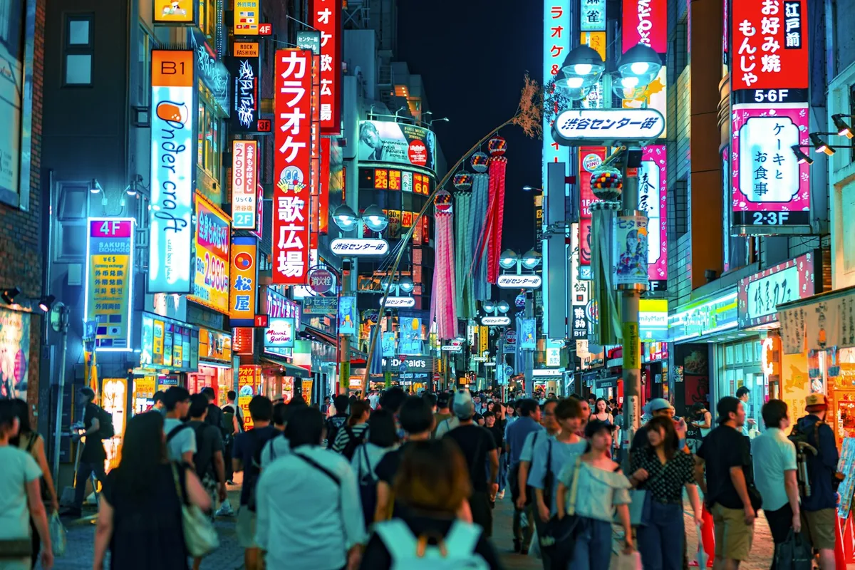 A crowd crossing a neon-lit street in Shibuya, Tokyo