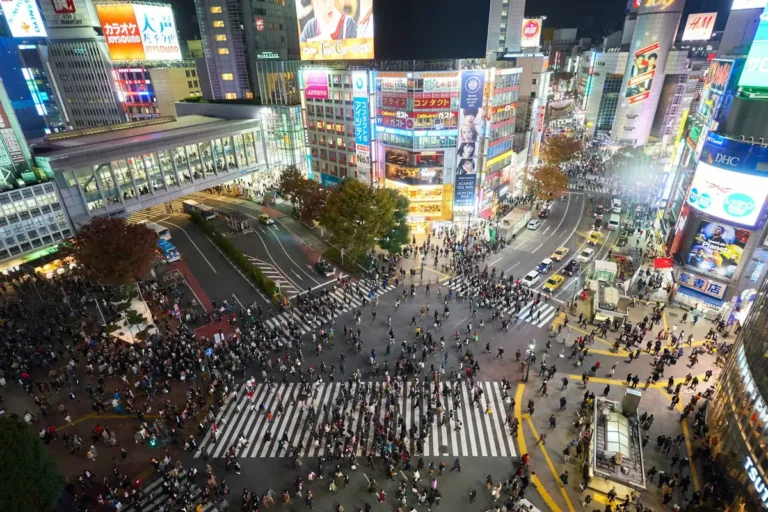 Crowds crossing the Shibuya Scramble Crossing at night in Tokyo