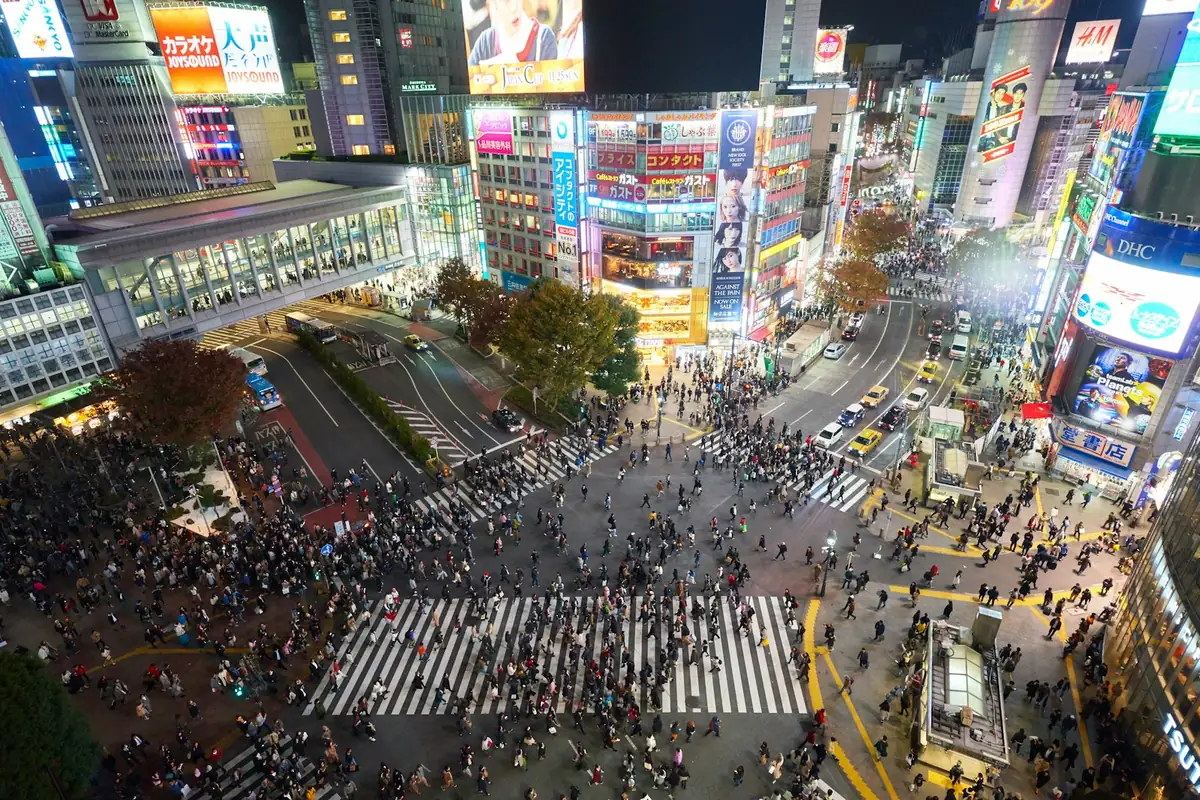 Menschenmassen überqueren nachts die Shibuya Scramble Crossing in Tokio
