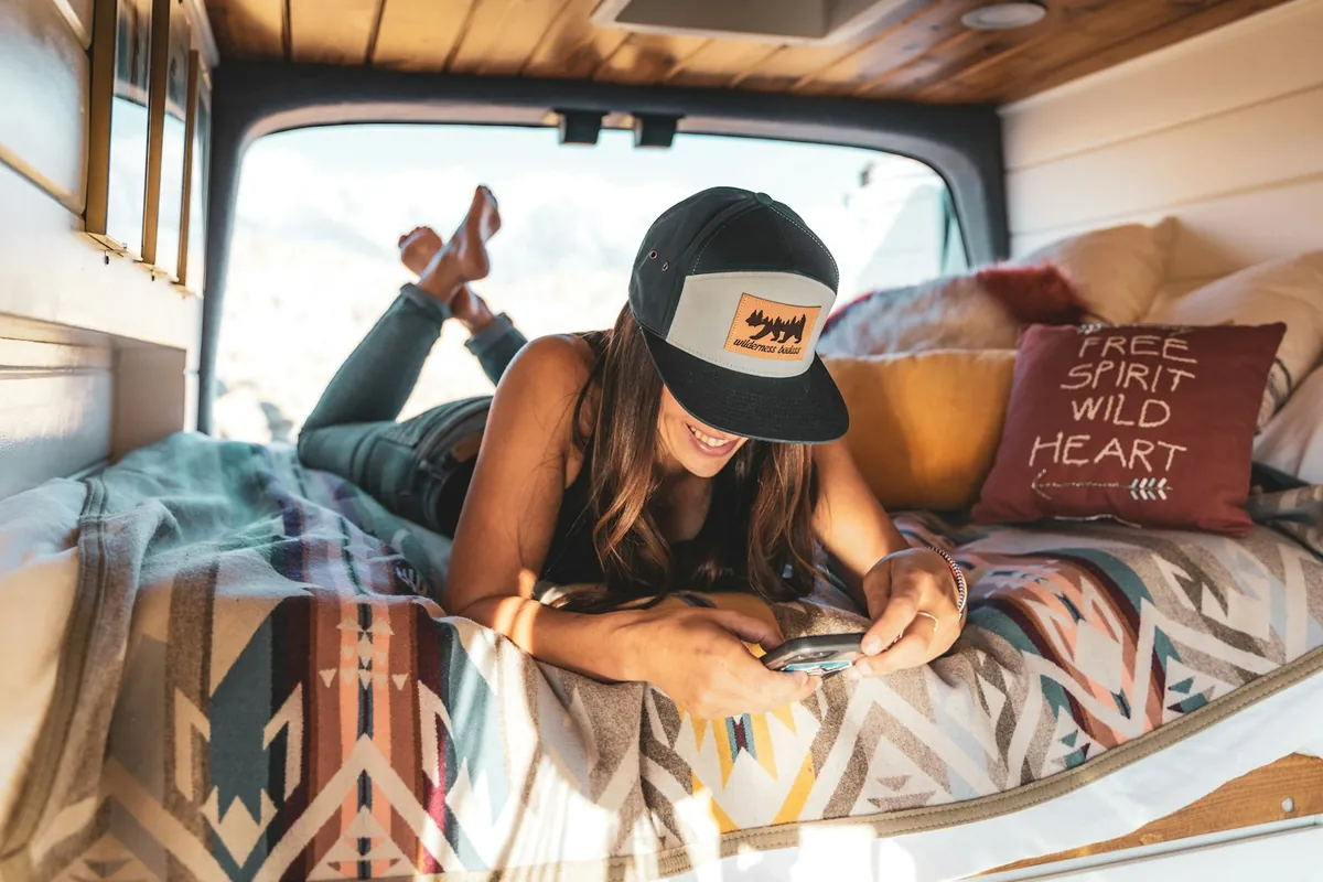 Woman relaxing on the bed inside a camper van
